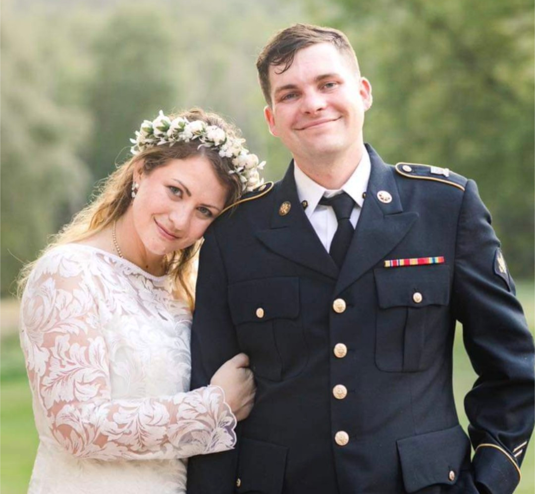 Bride in lace gown with groom in military dress uniform outdoors