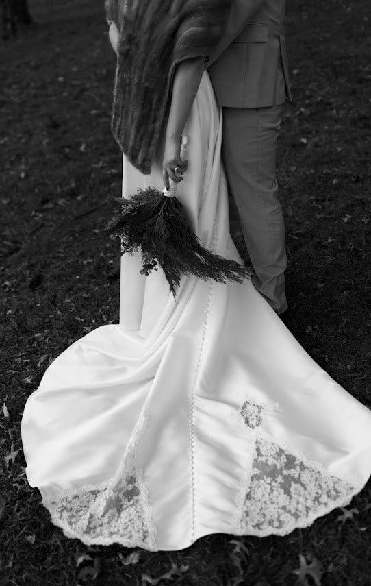Bride in satin gown with lace hem and fur wrap, black and white